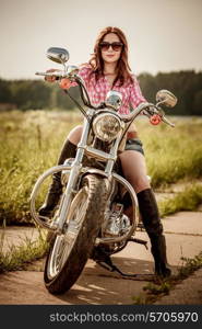 Biker girl with sunglasses sitting on motorcycle