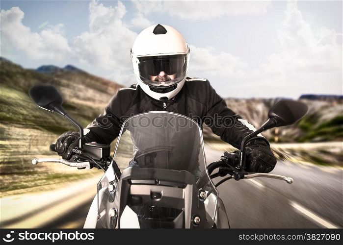Biker in helmet and black jacket riding on the road.