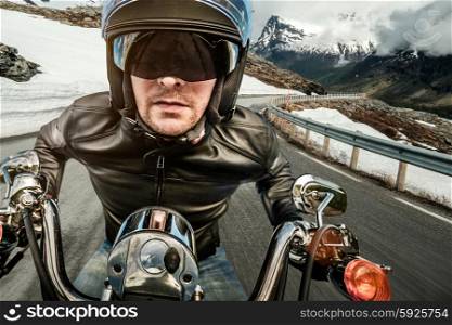 Biker in helmet and leather jacket racing on mountain serpentine.