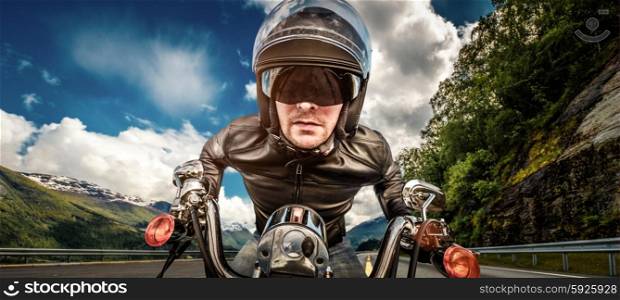 Biker in helmet and leather jacket racing on mountain serpentine.