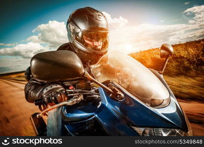 Biker in helmet and leather jacket racing on the road