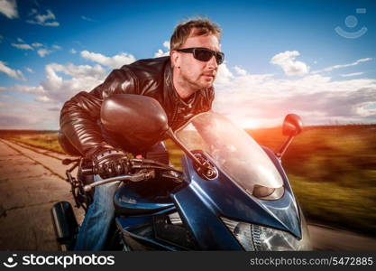 Biker in helmet and leather jacket racing on the road