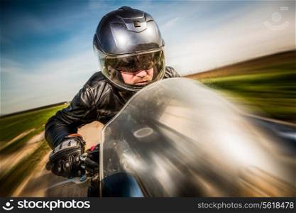 Biker in helmet and leather jacket racing on the road