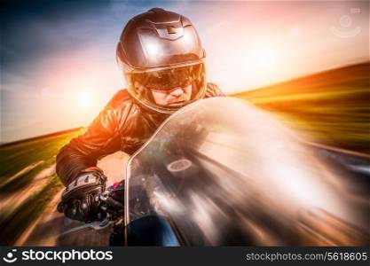 Biker in helmet and leather jacket racing on the road