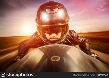 Biker in helmet and leather jacket racing on the road