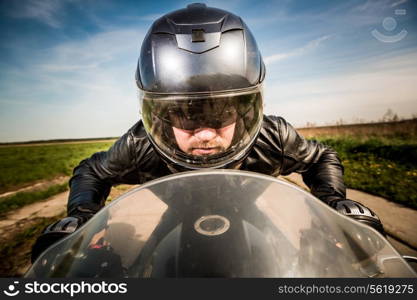 Biker in helmet and leather jacket racing on the road