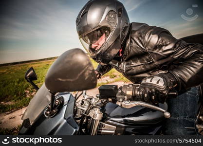 Biker in helmet and leather jacket racing on the road