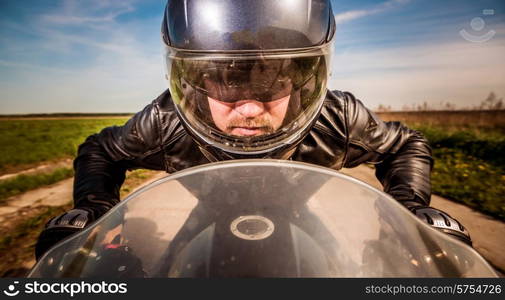 Biker in helmet and leather jacket racing on the road