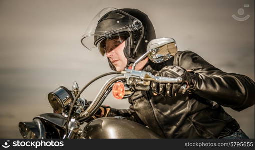 Biker in helmet and leather jacket racing on the road