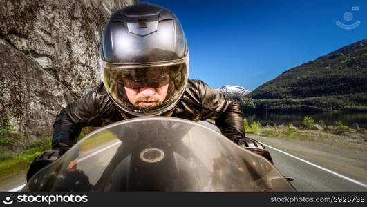 Biker in helmet and leather jacket racing on the road.