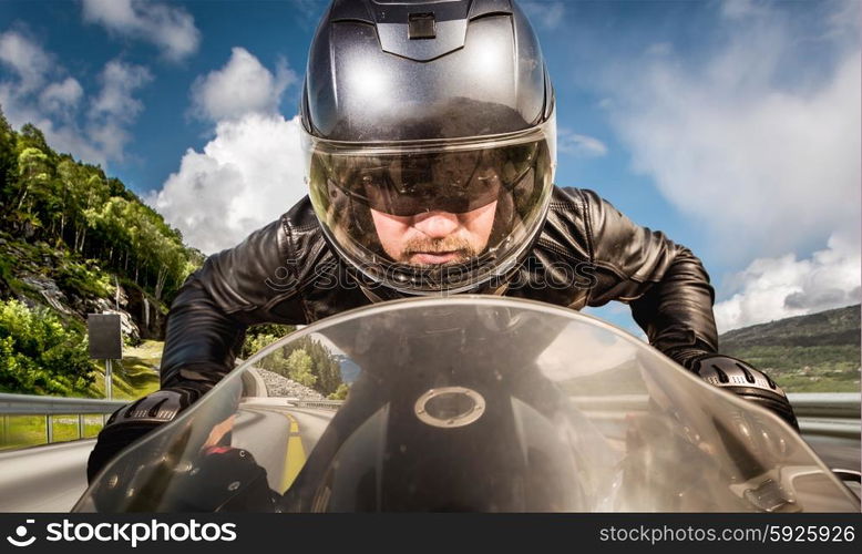 Biker in helmet and leather jacket racing on the road.