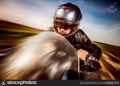 Biker in helmet and leather jacket racing on the road