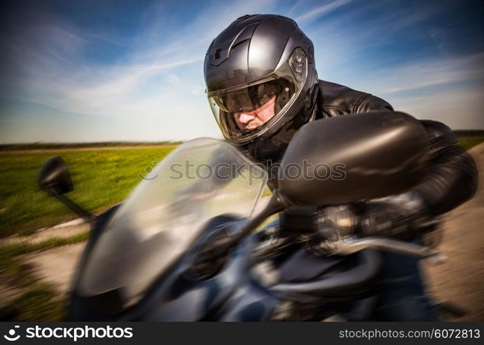 Biker in helmet and leather jacket racing on the road