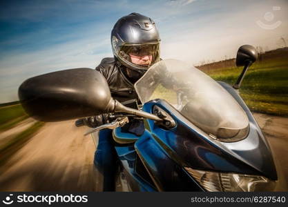 Biker in helmet and leather jacket racing on the road