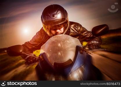 Biker in helmet and leather jacket racing on the road. Filter applied in post-production.