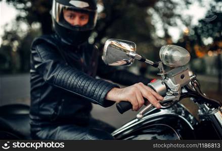 Biker in helmet poses on a motorcycle, classical chopper. Vintage bike, rider and his two-wheeled friend, freedom lifestyle, biking