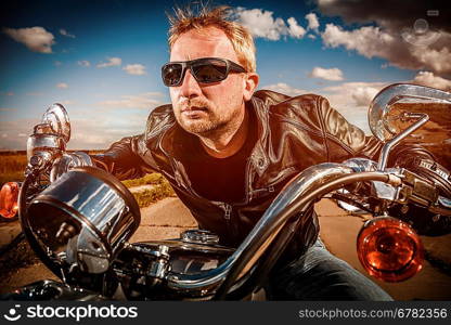 Biker in sunglasses and leather jacket racing on the road