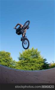 Biker jump high from jump box ramp performing big air trick.