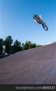 Biker jump high from jump box ramp performing dangerous 360 trick.