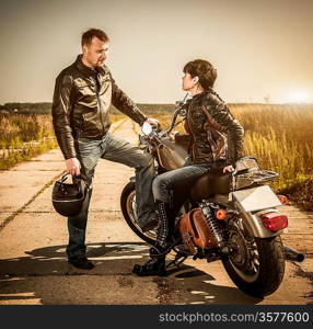 Biker man and girl sits on a bike