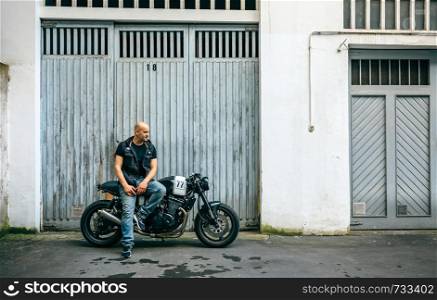 Biker posing with a custom motorcycle in front of the garage door. Biker posing with a motorcycle