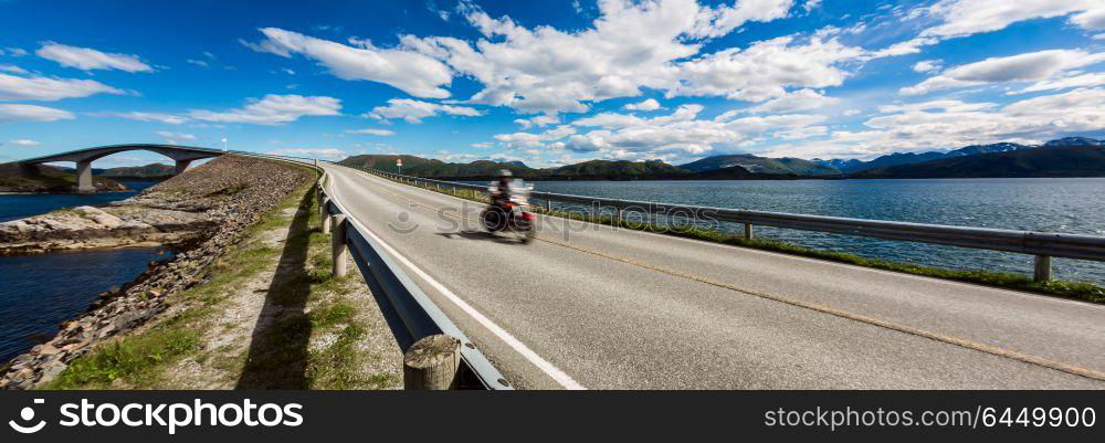 "Biker rides a road with Atlantic Road in Norway. Atlantic Ocean Road or the Atlantic Road (Atlanterhavsveien) been awarded the title as "Norwegian Construction of the Century". Biker in motion blur."