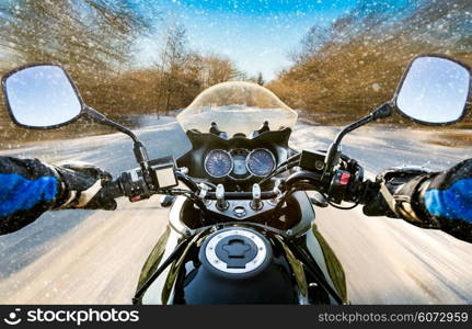 Biker rides on winter slippery road. First-person view.