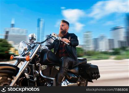 Biker riding on classical chopper, blured cityscape on background. Vintage bike, rider on motorcycle, asphalt road adventure, freedom lifestyle