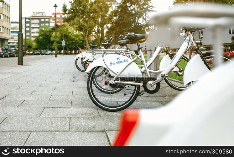 Bikes with customizable design parked in a rental station next to a park. Rental bikes with customizable design