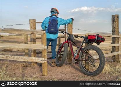 biking in Soapstone Prairie Natural Area near Fort Collins, male cyclist with a fat mountain bike is opening a gate in a cattle fence