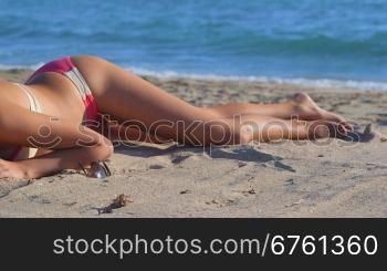 Bikini girl body lying on summer sandy beach by sea