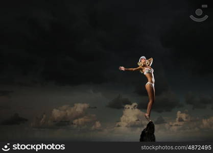 Bikini girl. Hot young dancing woman in white bikini on dark background