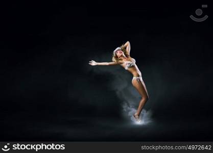 Bikini girl. Hot young dancing woman in white bikini on dark background