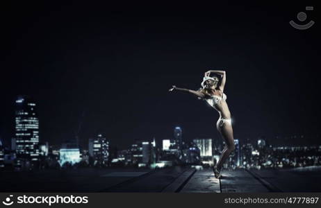 Bikini girl. Hot young dancing woman in white bikini on night city background