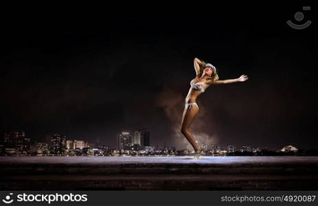 Bikini girl. Hot young dancing woman in white bikini on night city background