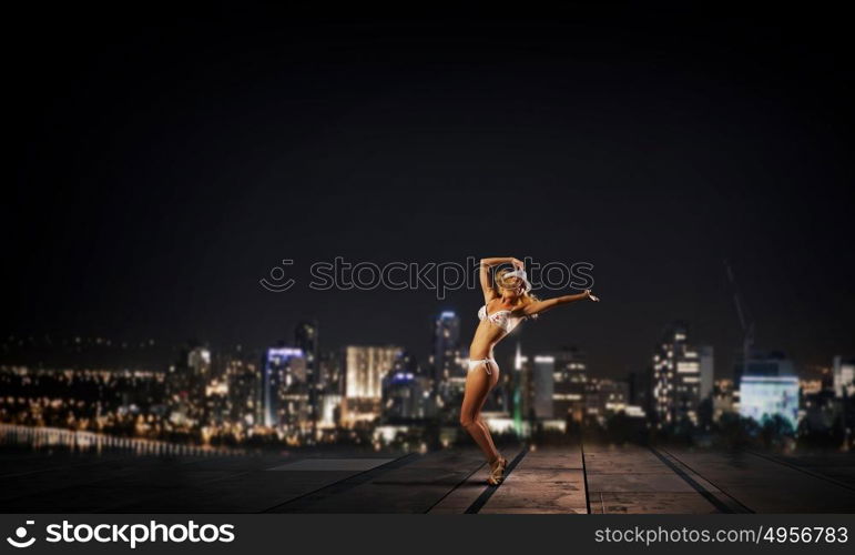 Bikini girl. Hot young dancing woman in white bikini on night city background