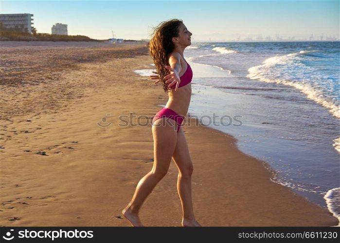 Bikini girl running to the beach shore water of Mediterranean sea