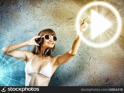 Bikini girl wearing headphones. Young attractive girl in white bikini touching icon