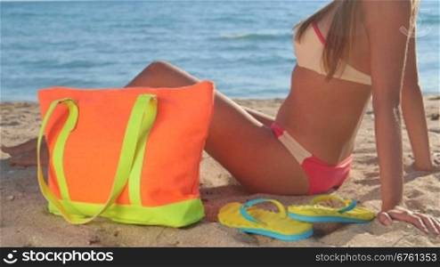 Bikini girl with colorful accessories on sandy beach