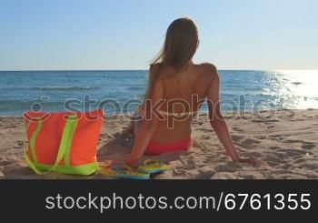 Bikini woman with colorful accessories enjoying summer beach vacation rear view