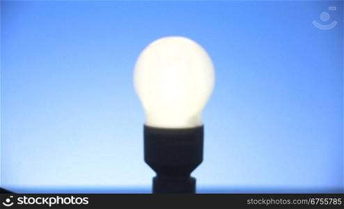 Bild einer Energiesparlampe wird scharf gestellt und Lampe geht an