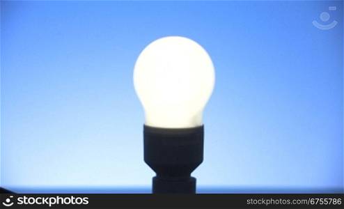 Bild einer Energiesparlampe wird scharf gestellt und Lampe wird angeschaltet