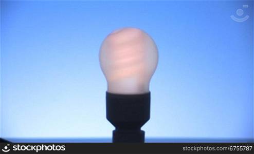 Bild einer Energiesparlampe wird scharf gestellt und Lampe wird angeschaltet