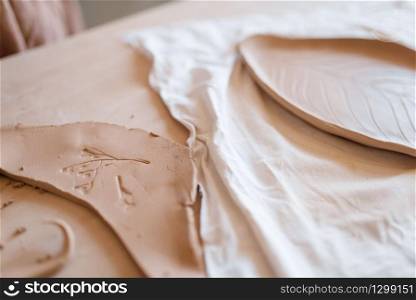 Billets for pottery with patterns, clay plate on wooden table in workshop, nobody. Handmade tableware molding and shaping