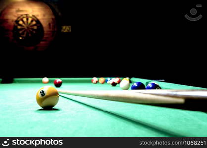 Billiards balls, key and a darts board on the wall