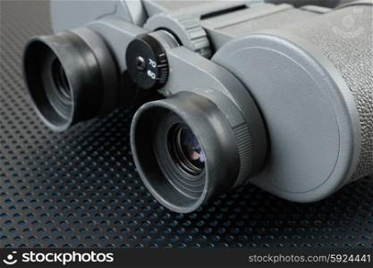Binoculars on a metallic background with perforation of round holes