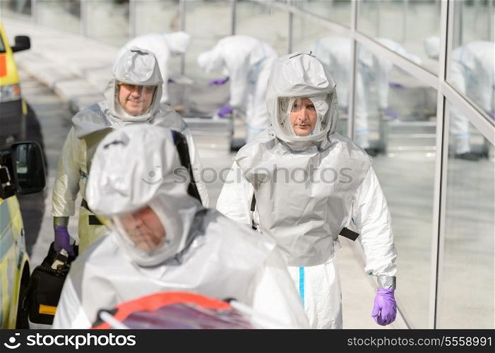 Biohazard medical team in protective uniform walking outside contaminated building