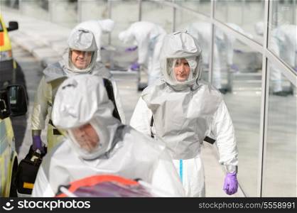 Biohazard medical team in protective uniform walking outside contaminated building