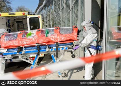 Biohazard medical team member with stretcher entering contaminated building