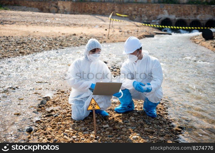 Biologist wear protective suit and mask collects sample of waste water from industry, problem environment, Ecologist sample taken dead fish to inspection and save data to laptop computer, Toxic water